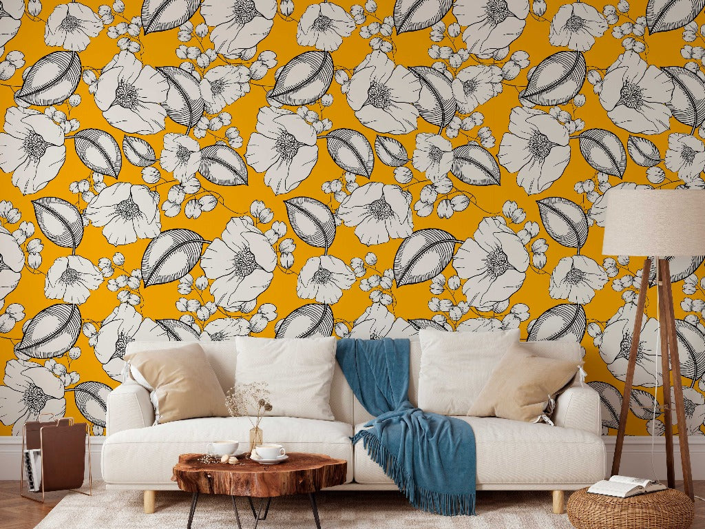 A cozy living room with a white sofa adorned with a blue throw blanket, a wooden coffee table, and a lamp, against Decor2Go Wallpaper Mural adorned with large white floral patterns.