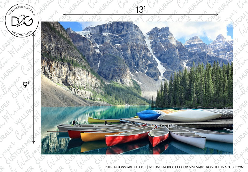 A serene Decor2Go Wallpaper Mural features multiple colorful canoes resting on the shore, surrounded by towering pine trees and jagged mountains under a clear blue sky.
