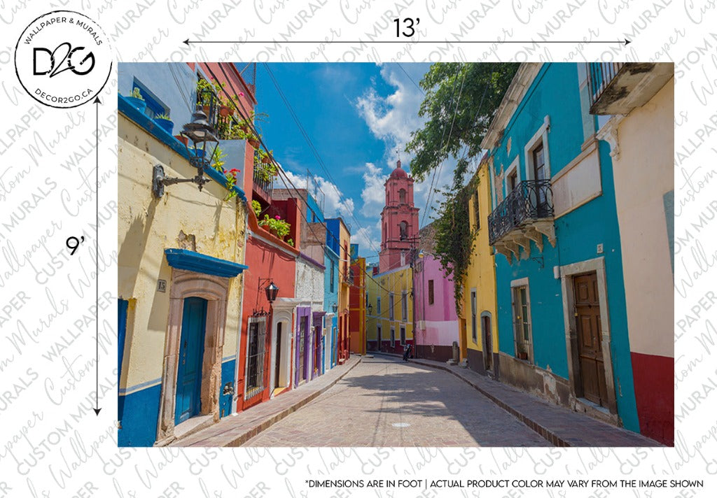 A vibrant street lined with colorful colonial buildings under a clear blue sky, featuring a custom-sized Decor2Go Wallpaper Mural, leading towards a pink and yellow church tower in the distance.