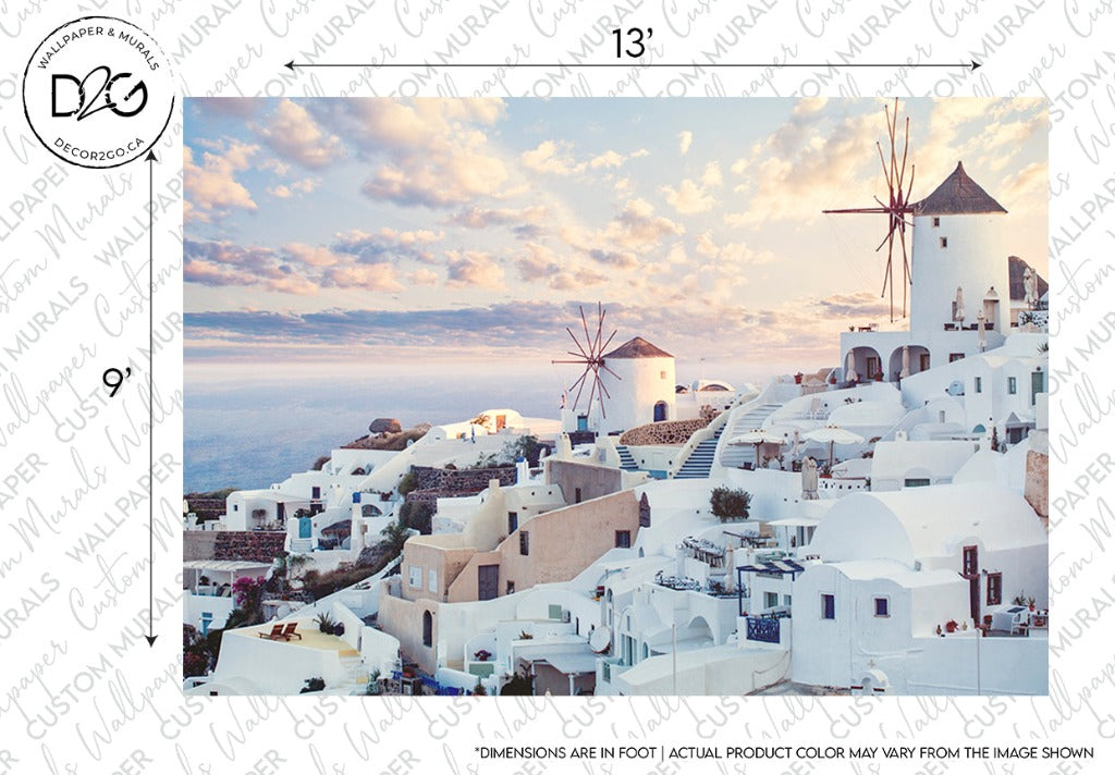 A picturesque view of a coastal village with white buildings on a hillside, featuring domed roofs and windmills. The sky is partly cloudy with a warm light, suggesting a sunrise or sunset. The sea glistens in the background. Santorini Skyline Wallpaper Mural by Decor2Go Wallpaper Mural embodies this Mediterranean aesthetic with custom sizing available.