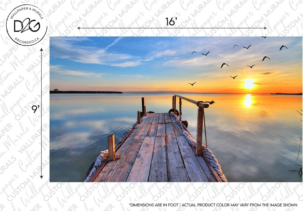 A wooden dock extends over calm water towards a vibrant sunset, capturing the natural beauty of the scene. Birds fly in the sky as sunlight reflects on the water's surface, perfect for a Sunset Birds Flying Wallpaper Mural by Decor2Go Wallpaper Mural. The weathered dock, crafted from high-quality materials, has ropes tied at the ends. Surrounding are dimensions noting 16 feet by 9 feet.