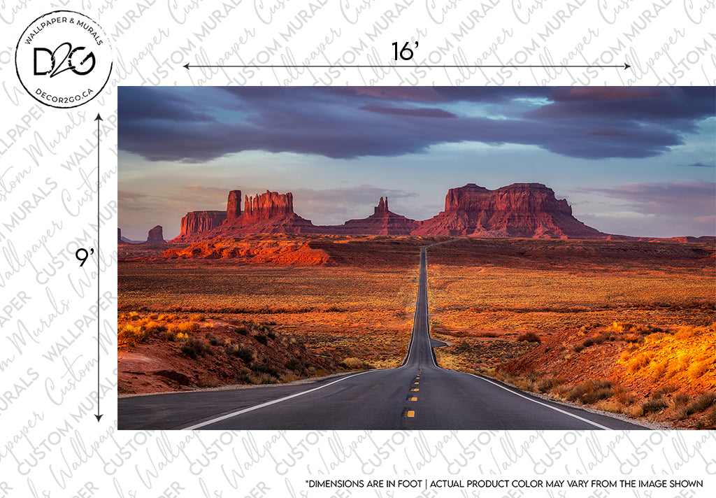 A long road stretching towards tall rocky formations under a vibrant sunset sky, with vast desert landscape on either side. This is the perfect Decor2Go Wallpaper Mural for travel fanatics. Watermarks and dimensions.