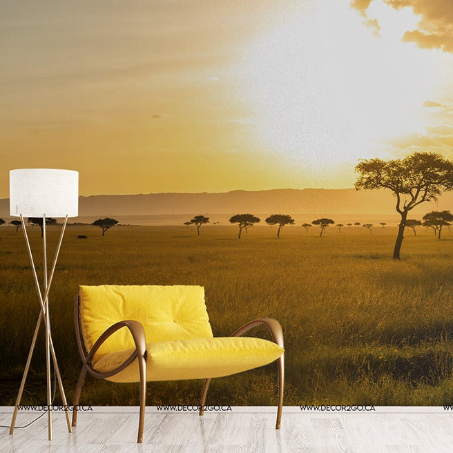 A stylish yellow chair and a standing lamp in a room featuring a Decor2Go Wallpaper Mural of an African Savanna landscape during sunset.