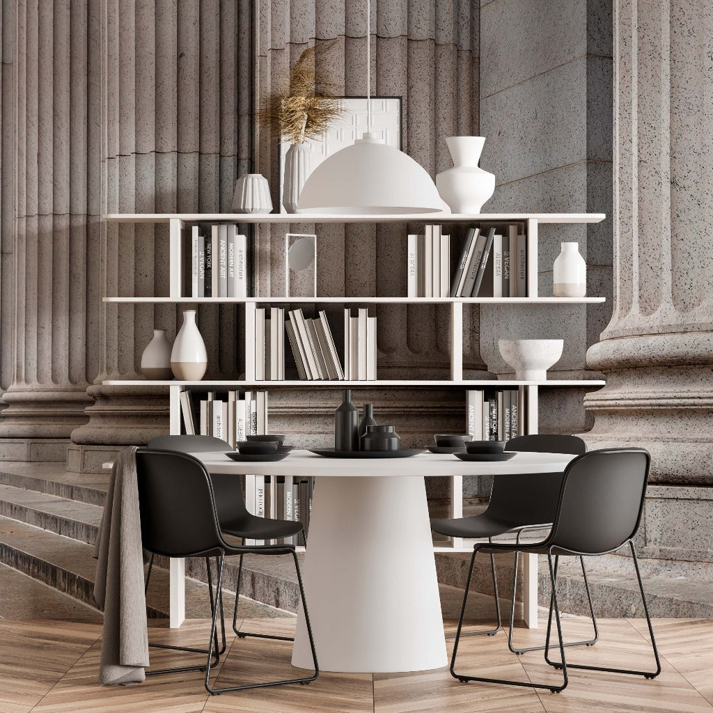 A stylish, modern dining space with a white circular table, black chairs, and a white shelving unit filled with various vases, set against a backdrop of elegant Decor2Go Wallpaper Mural featuring Ancient Pillars.