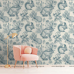 Pink chair with a wallpaper mural in blue with rabbits, plants, flowers, and squirrels 