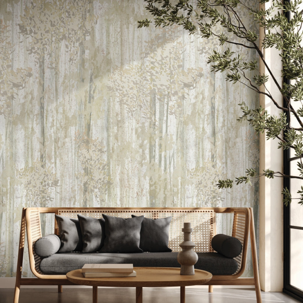 A modern living room with a wooden sofa, black and gray cushions, a round coffee table, and a leafy plant by the window features the Aspen Grove Beige Wallpaper Mural (2 Panels) by York Wallcoverings as a subtle botanical accent wall.