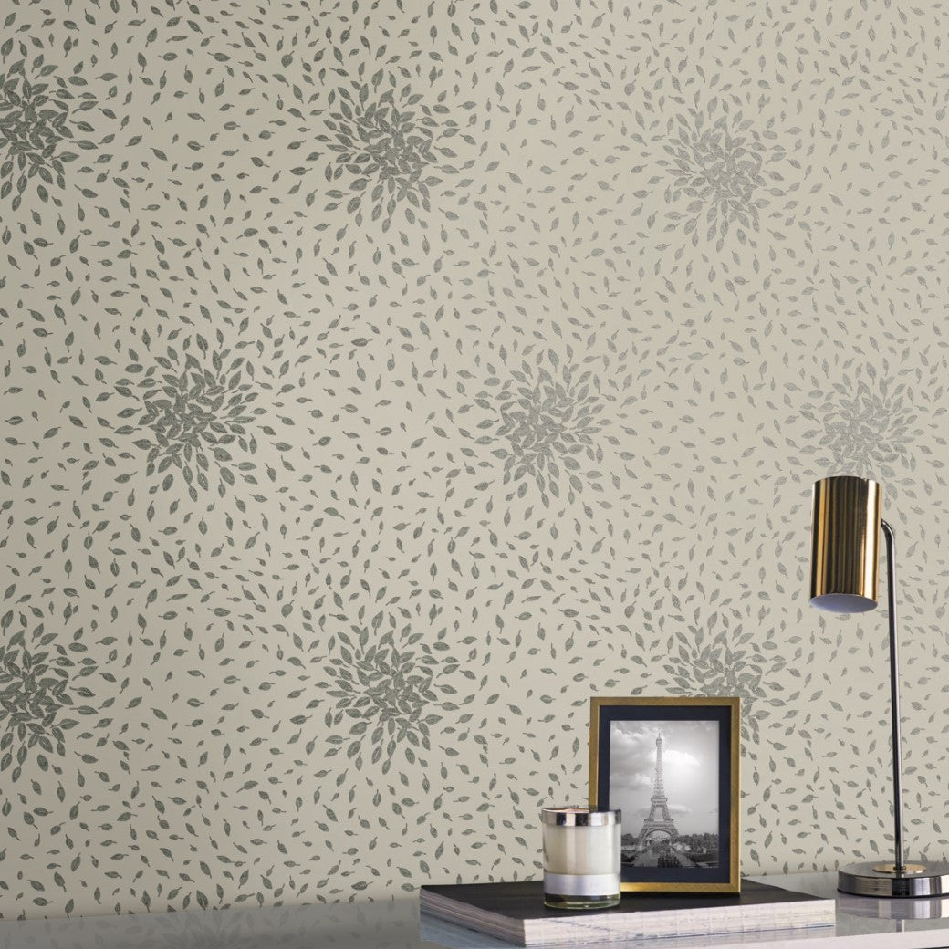 A contemporary aesthetic graces the space with York Wallcoverings' Beige & Silver Petite Leaves Wallpaper. The table features a gold lamp, a framed black-and-white Eiffel Tower photo, and a silver candle holder, adding metallic shapes to the ensemble.