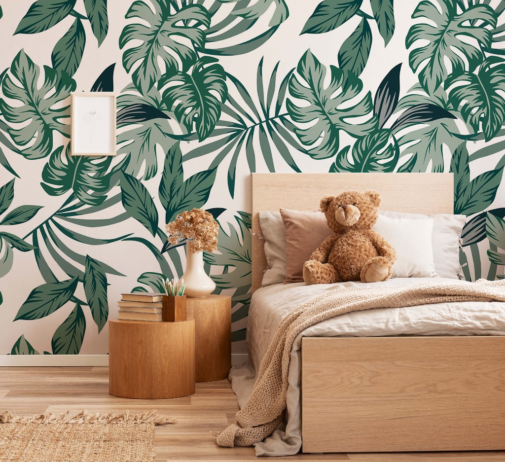 A cozy bedroom with Decor2Go Wallpaper Mural's Big Green Leaves Wallpaper Mural, featuring a wooden bed flanked by a nightstand with books, a teddy bear sitting on the bed, and a small framed poster on the wall