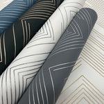 Four rolls of York Wallcoverings' Black & Gold Polished Chevron Wallpaper, part of the Modern Metals Collection, feature geometric patterns with overlapping zigzag lines in black, white, gray, and blue metallic accents for a modern and stylish look.