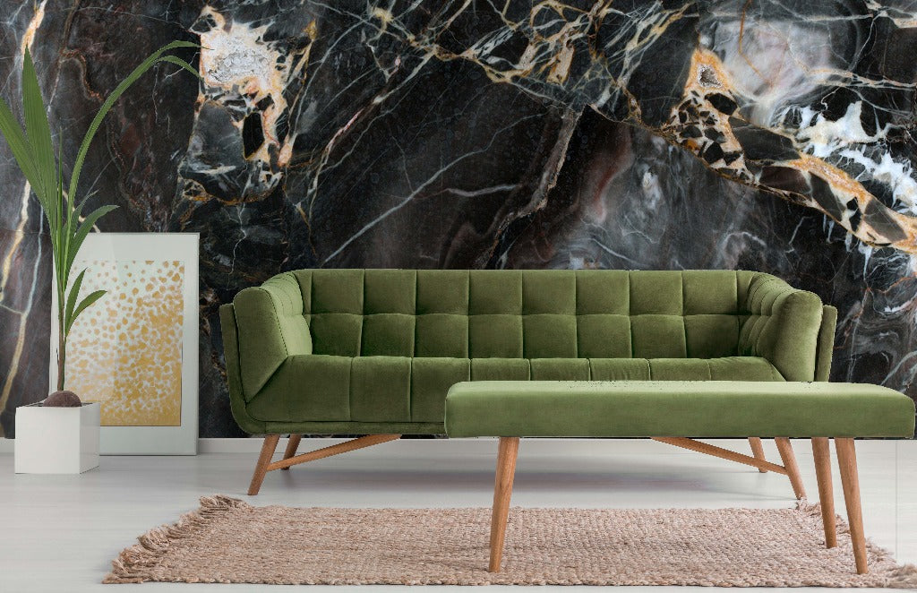 A stylish interior featuring a green velvet sofa against a dramatic Decor2Go Wallpaper Mural with gold accents. A beige rug, potted plant, and abstract art piece complete the scene.