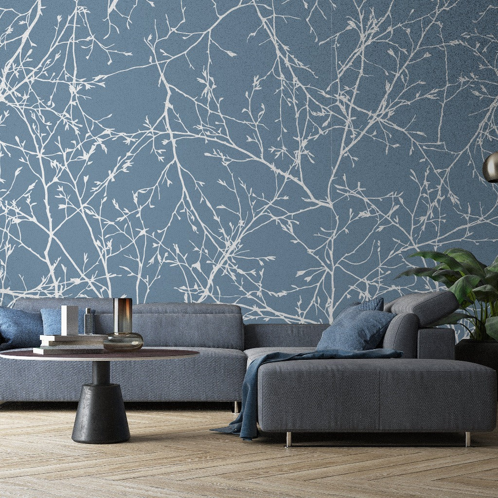 Living Room - A modern living room featuring a large, gray sectional sofa against a blue wall with Decor2Go Wallpaper Mural. There's a black round coffee table, floor lamp, and a potted plant.