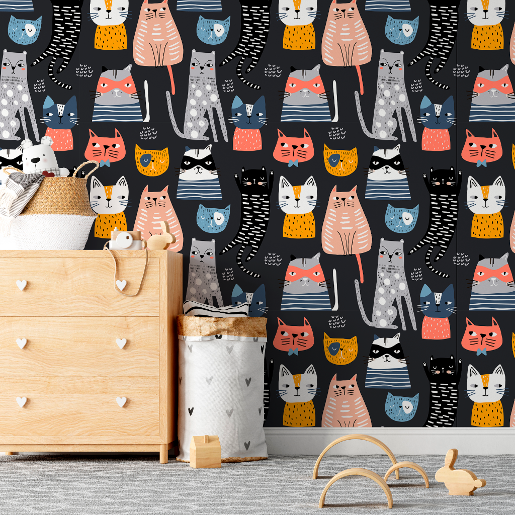 A nursery room featuring a wall covered in Decor2Go Wallpaper Mural's Cartoon Cats Wallpaper Mural with colorful cat illustrations, a wooden crib, a storage basket, and a toy on the floor.