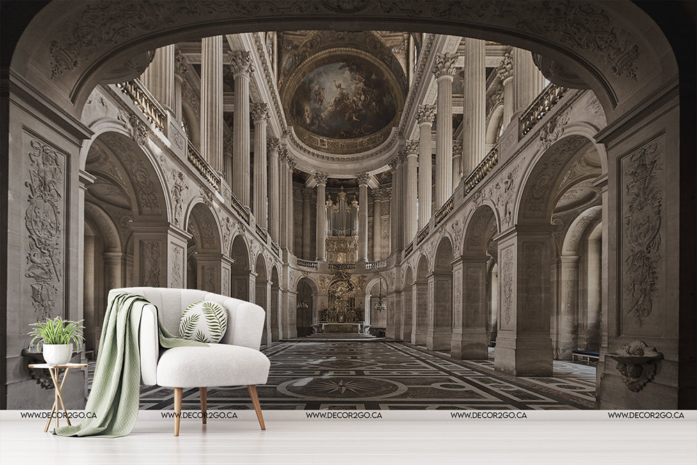 An elegant modern living room setup featuring a white armchair, a throw blanket, and a side table with plant, against a large Cathedral Grande Wallpaper Mural by Decor2Go Wallpaper Mural of a grand, ornate historical interior.