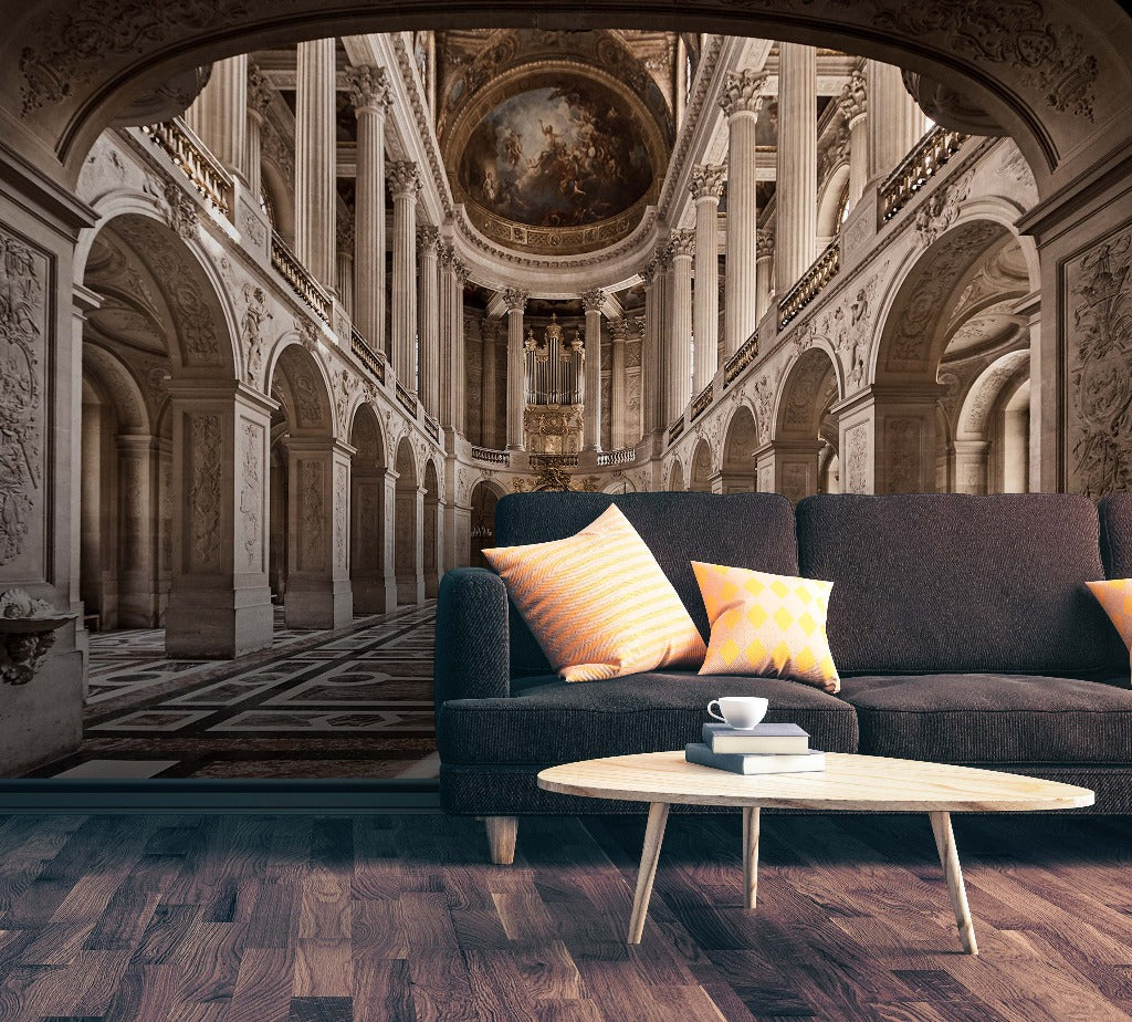 A modern dark blue sofa with colorful pillows in a grand, ornately decorated European palace hall featuring the Decor2Go Wallpaper Mural, arches, frescoes, and intricate floor designs. A small white coffee