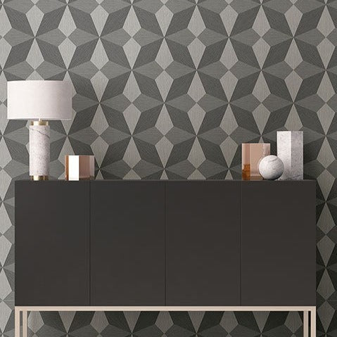 Modern interior design featuring a sleek, dark grey sideboard under **Charcoal Cerium Concrete Geometric (56 SqFt) by York Wallcoverings** adorned with geometric patterns in shades of grey. Decorative items on the sideboard include a marble lamp, a spherical object, and a couple of metallic and marble vases.