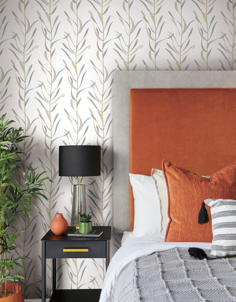 A stylish bedroom corner featuring a gray upholstered bed with an orange headboard, a black bedside table with a lamp, and removable York Wallcoverings SureStrip Chloe Vine River Rock Wallpaper Beige, Grey (60 Sq.Ft.). A potted plant adds a touch.