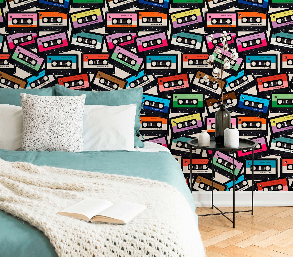 A cozy bedroom corner with a bed covered in a teal blanket and white knit throw, situated against a vibrant wall adorned with a custom-sized mural of Decor2Go Wallpaper Mural Coloured Cassette Wallpaper Mural.