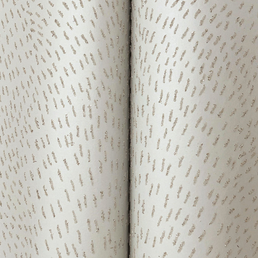 Close-up of York Wallcoverings Dew Drop Beige Wallpaper (60 SqFt), featuring light-colored, textured non-woven material with small, irregular raised dashes in curved lines for a subtle, elegant look.