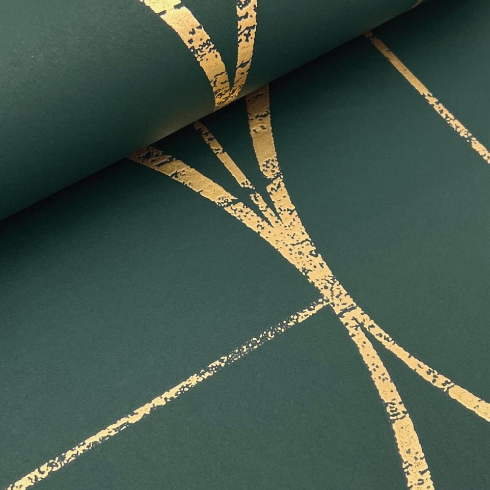 A close-up of the Emerald & Gold Sun Circles Wallpaper by York Wallcoverings showcases a dark green Art Deco design with elegant, thin gold lines forming an abstract geometric pattern. The smooth texture and metallic finish create a lustrous sheen.