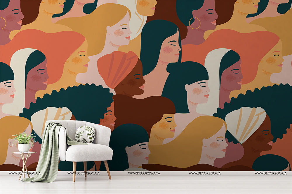 An artistic Femme Fatale Wallpaper Mural celebrating women's empowerment, featuring a diverse collection of stylized female faces in a variety of colors and shapes, with a modern chair and plant in front by Decor2Go Wallpaper Mural.
