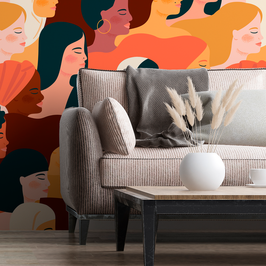 A stylish living room with a beige couch and a white vase with dried pampas grass on a wooden coffee table. The wall behind is adorned with Decor2Go Wallpaper Mural of abstract female faces, symbolizing Femme Fatale.