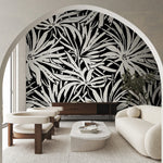 Modern living room with cream furniture, a white oval coffee table, and York Wallcoverings’ Floral Canopy Black Wallpaper Mural as a striking feature wall, viewed through a large archway.