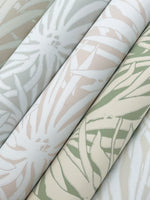 Three rolls of York Wallcoverings' Floral Canopy Cream Wallpaper (60 SqFt), featuring soft pastel tropical leaf patterns in mint green, beige, and cream, are arranged diagonally and closely together.