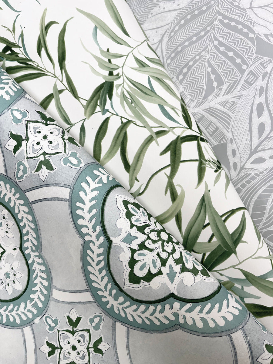 A close-up image of three different patterned wallpapers. The top one features green leafy vines on a white background, capturing botanical elegance. The middle one has intricate light blue and white floral designs, while the bottom showcases gray patterns with various shapes and lines. York Wallcoverings Garden Trellis Rain Wallpaper Blue, Grey (60 Sq.Ft.) offers easy installation and removal.