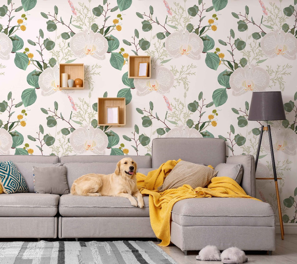 A golden retriever lounges on a gray sofa in a living room with a Decor2Go Wallpaper Mural background. A knitted yellow throw is draped across the sofa, beside a floor lamp.
