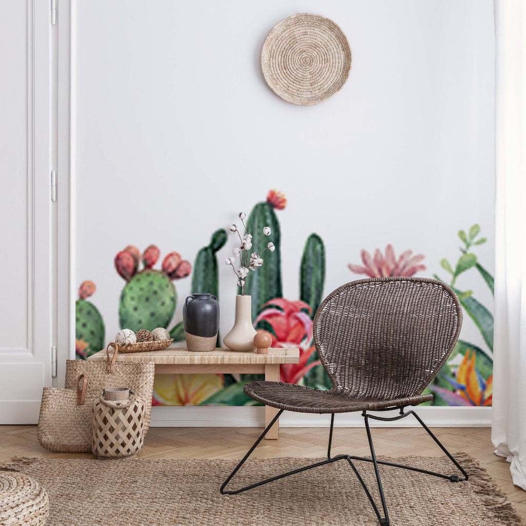 A stylish room featuring a wicker chair, a small wooden table with vases, baskets, and a decorative wall hanging, against a vibrant Decor2Go Garden of Cactus Wallpaper Mural.