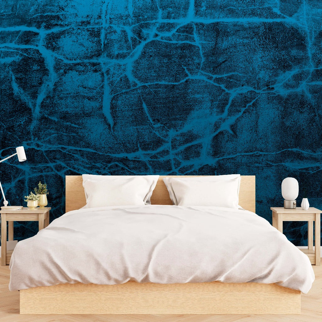 A minimalist bedroom featuring a wooden bed with white bedding, two bedside tables with lamps, and a vibrant blue Decor2Go Wallpaper Mural behind the bed.