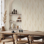 A dining area with wooden chairs and table, simple tableware, and shelves displaying vases and candles. Decor in earthy tones features York Wallcoverings’ Graceful Willow Pale Straw Wallpaper (60 SqFt) with a subtle vertical leaf pattern.