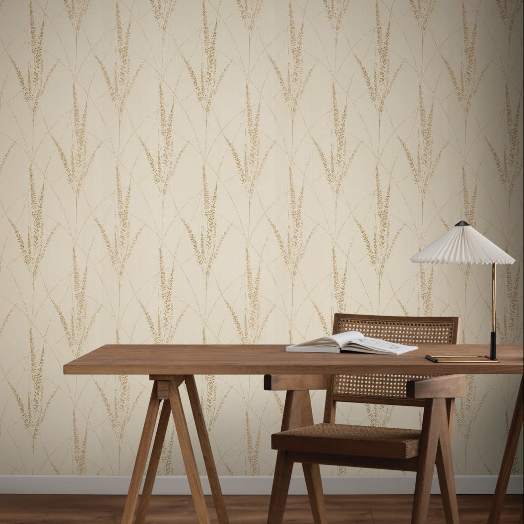 Home Office - A minimalist with a wooden desk and chair, open book, and white table lamp set against York Wallcoverings’ Graceful Willow Pale Straw Wallpaper (60 SqFt) featuring a subtle, repeating leafy pattern