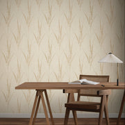 Home Office - A minimalist with a wooden desk and chair, open book, and white table lamp set against York Wallcoverings’ Graceful Willow Pale Straw Wallpaper (60 SqFt) featuring a subtle, repeating leafy pattern