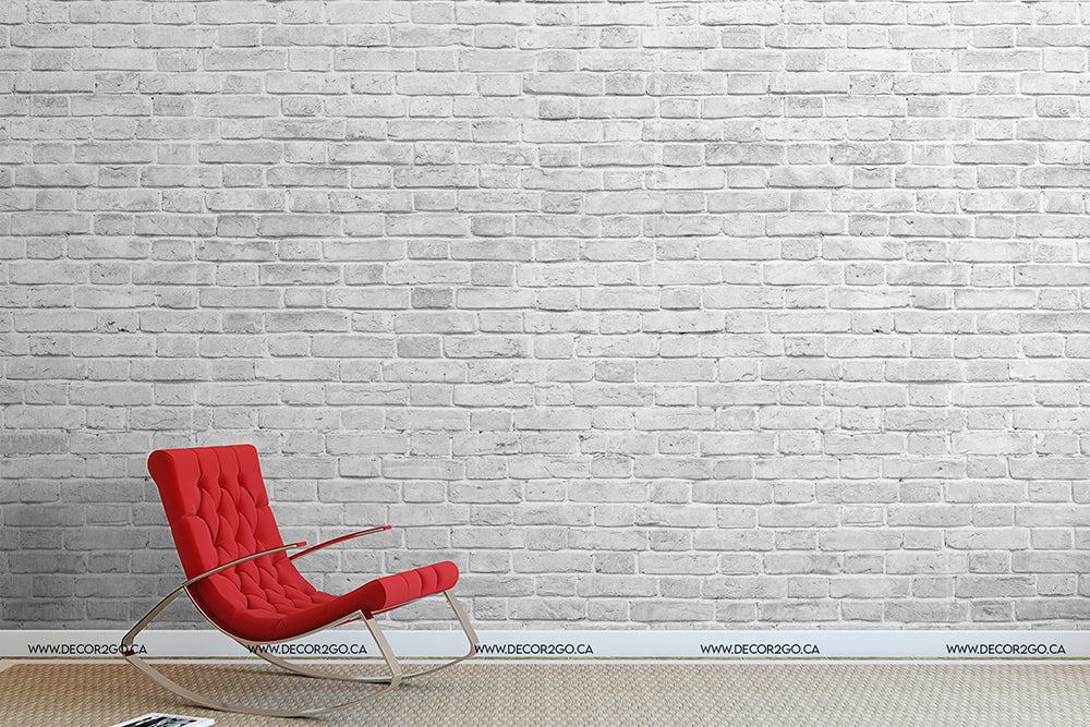 A minimalist room with a Decor2Go Great White Wall Wallpaper Mural and a vibrant red modern chair against it. The floor is simple, light grey, adding contrast to the scene.