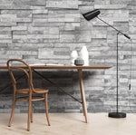 A modern workspace featuring a bentwood chair and a round table with a notebook and ceramic vases under a floor lamp, against an Grey Stone Wall Wallpaper Mural by Decor2Go Wallpaper Mural.
