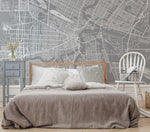 A modern bedroom with a grey Decor2Go Wallpaper Mural Winnipeg Wallpaper Mural, white rocking chair, and blue nightstand, against a wall featuring an architectural wall design of Winnipeg.