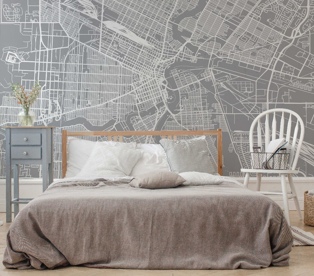 A modern bedroom with a grey Decor2Go Wallpaper Mural Winnipeg Wallpaper Mural, white rocking chair, and blue nightstand, against a wall featuring an architectural wall design of Winnipeg.
