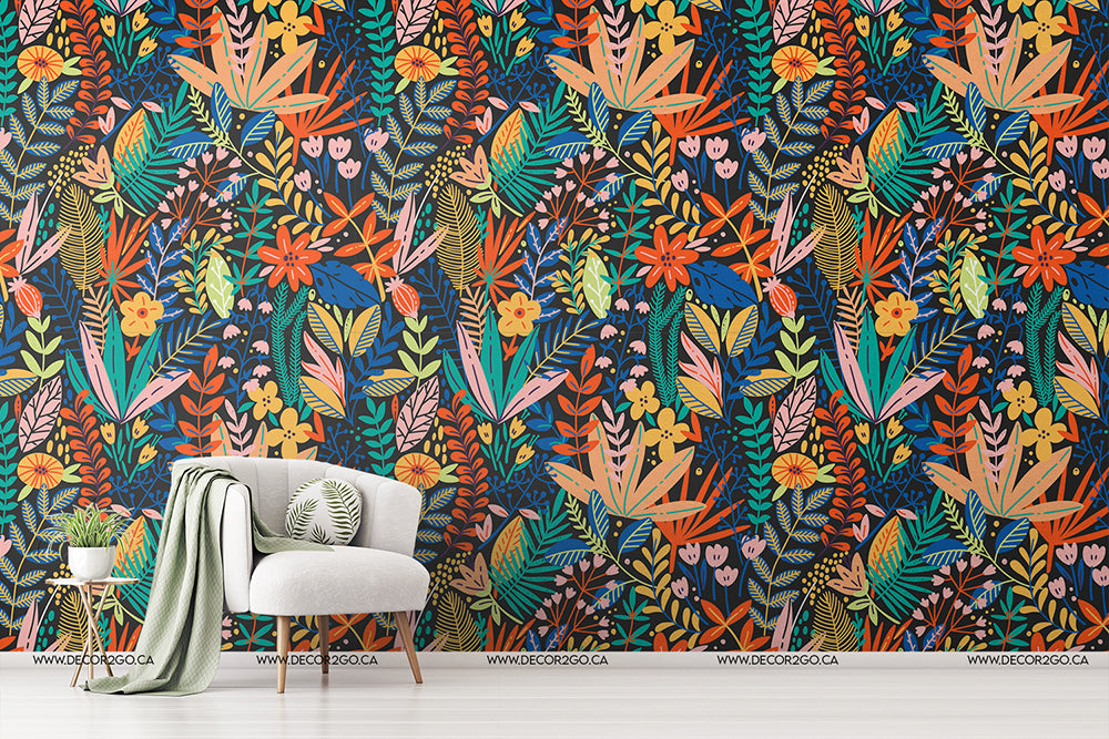 A vibrant and colorful Heart of the Jungle wallpaper mural by Decor2Go Wallpaper Mural featuring a variety of tropical flora in multiple colors. A white armchair with a green cushion and a blanket is placed in front of the wall.