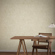 Home Office - A minimalist with a wooden desk, chair, open book, notebook, and white pleated lamp sits against a beige wall covered in York Wallcoverings' Impression Sand Wallpaper—ideal for contemporary interiors