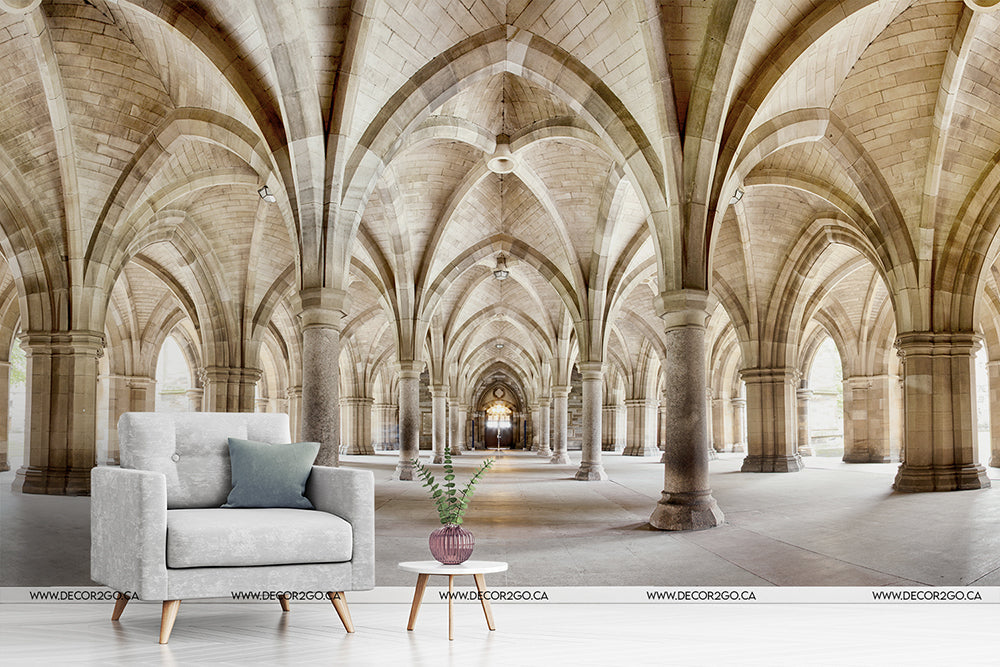 Living Room - A stylized image combining a modern living room setup with a grey armchair and side table inside Glasgow University cloister, featuring arched ceilings and Gothic architectural elements by Decor2Go Wallpaper Mural's Infinite Paths Wallpaper Mural.