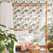 Bedroom - A cozy with York Wallcoverings' Lady Slipper wallpaper, featuring a wooden canopy bed draped with white sheer curtains, surrounded by lush green plants and a small table with drinks