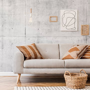 Living Room - A stylish living room featuring a modern grey sofa with decorative brown pillows, set against a Decor2Go Wallpaper Mural with minimalist art and hanging geometric lights. A woven basket sits by the sofa.