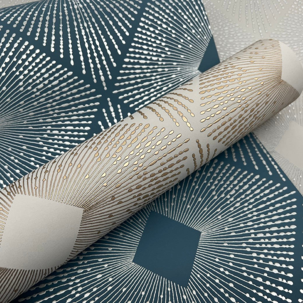 Close-up of rolled York Wallcoverings' Light Grey & Silver Harlowe Wallpaper (57 SqFt) showcasing a radiant design with metallic gold and silver lines radiating from a central point on a deep teal background for a starburst effect.