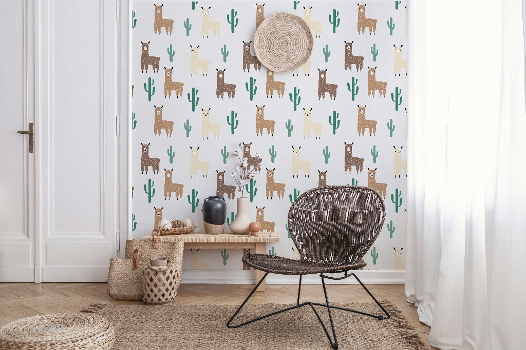 A cozy children's room corner with a rattan chair, complemented by a straw hat on the wall and a side bench displaying ceramics and a plant, against Decor2Go Wallpaper Mural with Llama and Cactus Pattern.