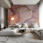 A modern living room features a large white sectional sofa and round wooden coffee table. Decor2Go's Pink and Gold Marble Wallpaper Mural adds a luxurious touch to the wall. A spherical lamp glows in the corner, while sheer curtains on a tall window allow natural light to filter through.