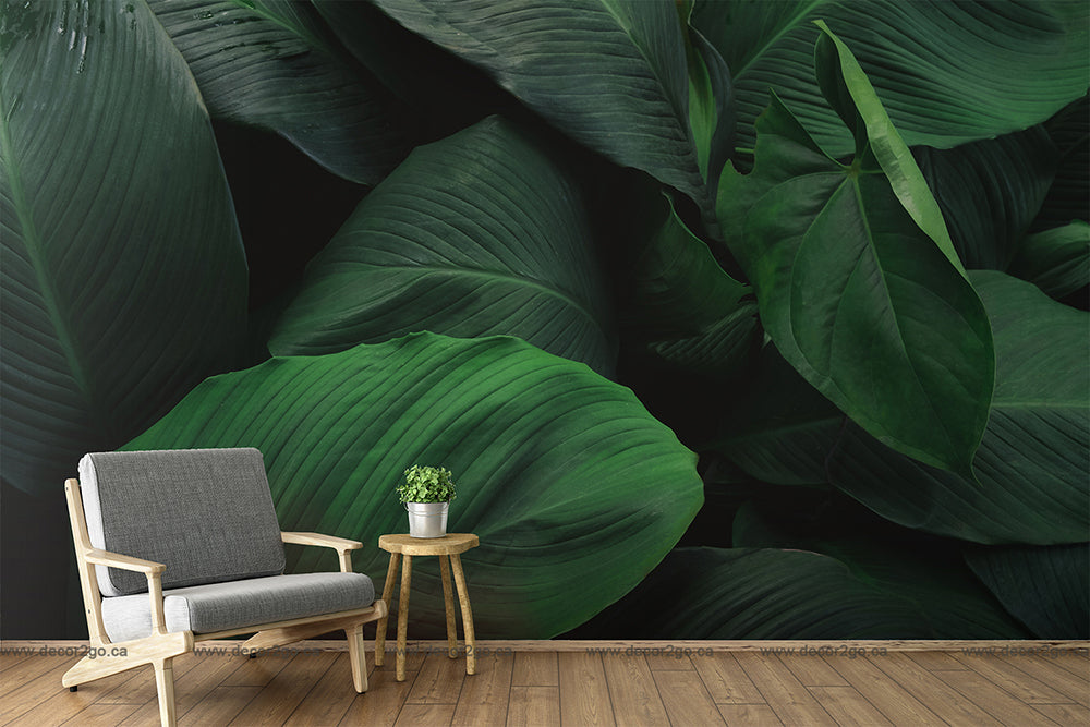 A modern chair and a small natural wood side table with a potted plant are placed against a large, detailed Decor2Go Wallpaper Mural in a spacious room.