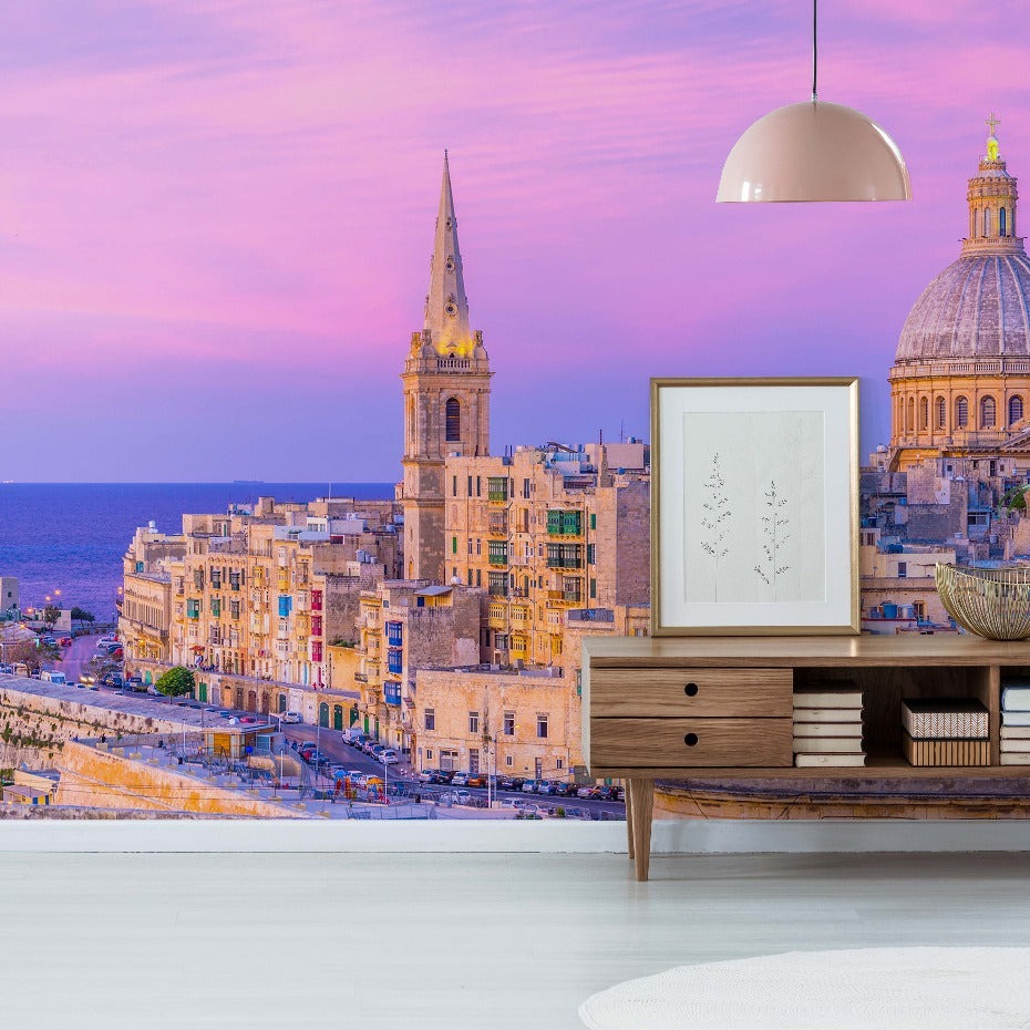 Modern living room with stylish furniture overlooking a scenic city with historic architectural buildings under a vibrant sunset sky, enhanced by a Decor2Go Wallpaper Mural.