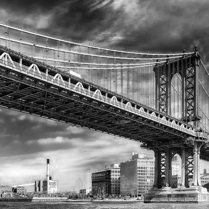 Black and white image of the large Decor2Go Wallpaper Mural stretching over a river with urban buildings in the background under a cloudy sky.