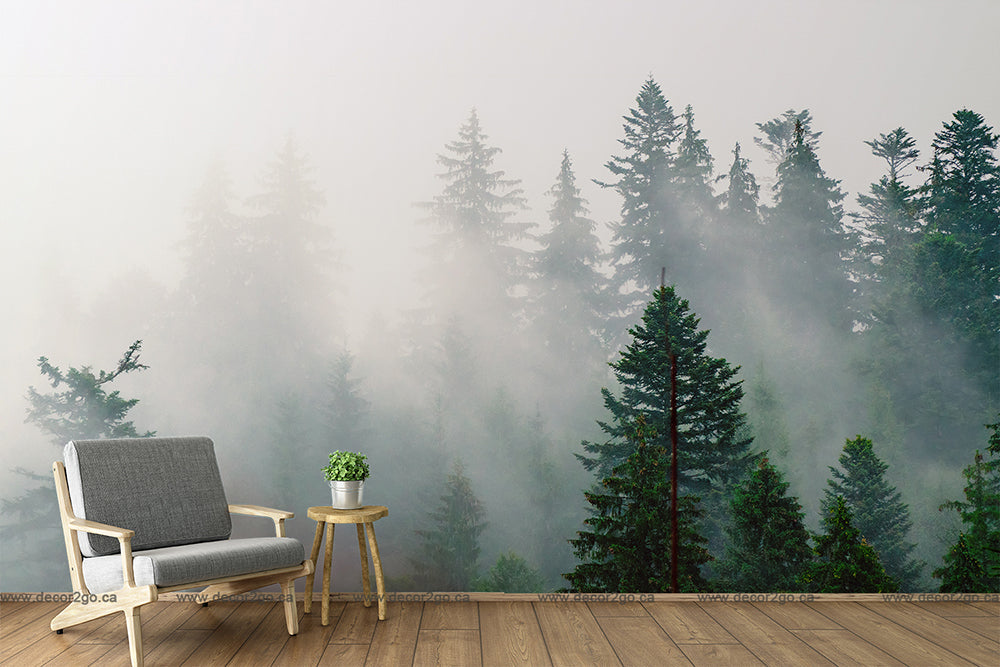 A modern living room with a single gray armchair and a small wooden side table with a potted plant, set against a Decor2Go Wallpaper Mural of the Misty Forest.